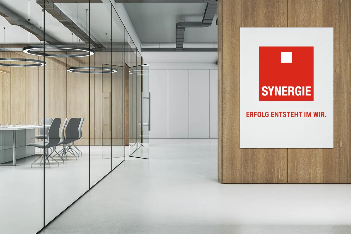 Innenraumaufnahme einer Niederlassung von Synergie zeigt ein Büro und an der Wand das Logo mit Claim